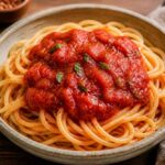 Spaghetti z klopsikami i sosem pomidorowym, udekorowane świeżą bazylią