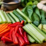 Pokrojone marchewki, papryki, ogórki, seler naciowy i zielone warzywa na drewnianej desce